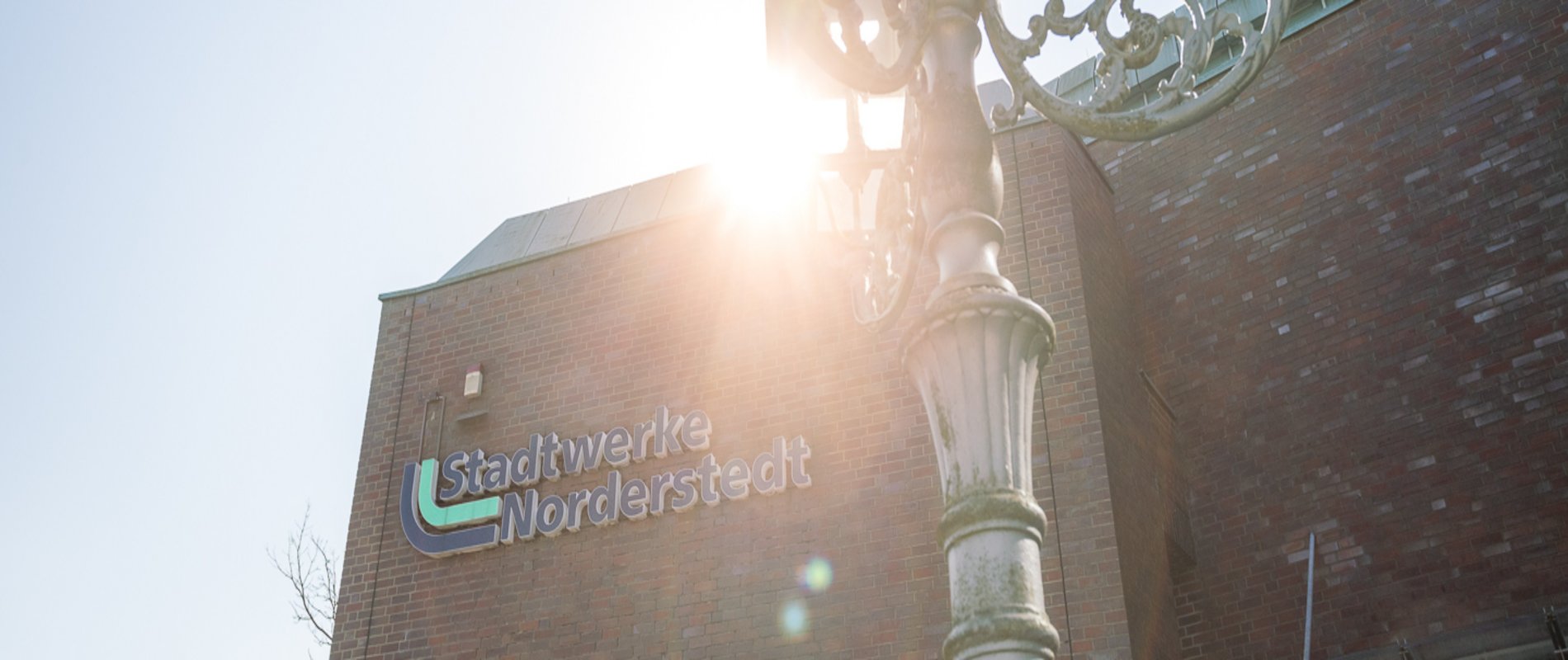 das Stadtwerke Norderstedt Logo am Hauptgebäude der Stadtwerke Norderstedt, die Sonne scheint über dem Gebäude