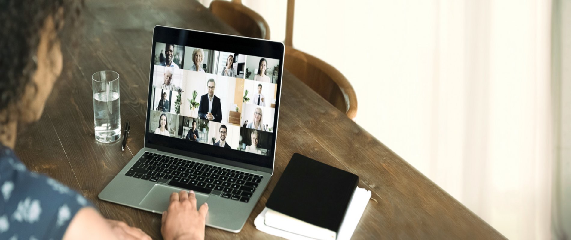 eine Frau sitzt am Laptop in einer geschäftlichen Video-Konferenz