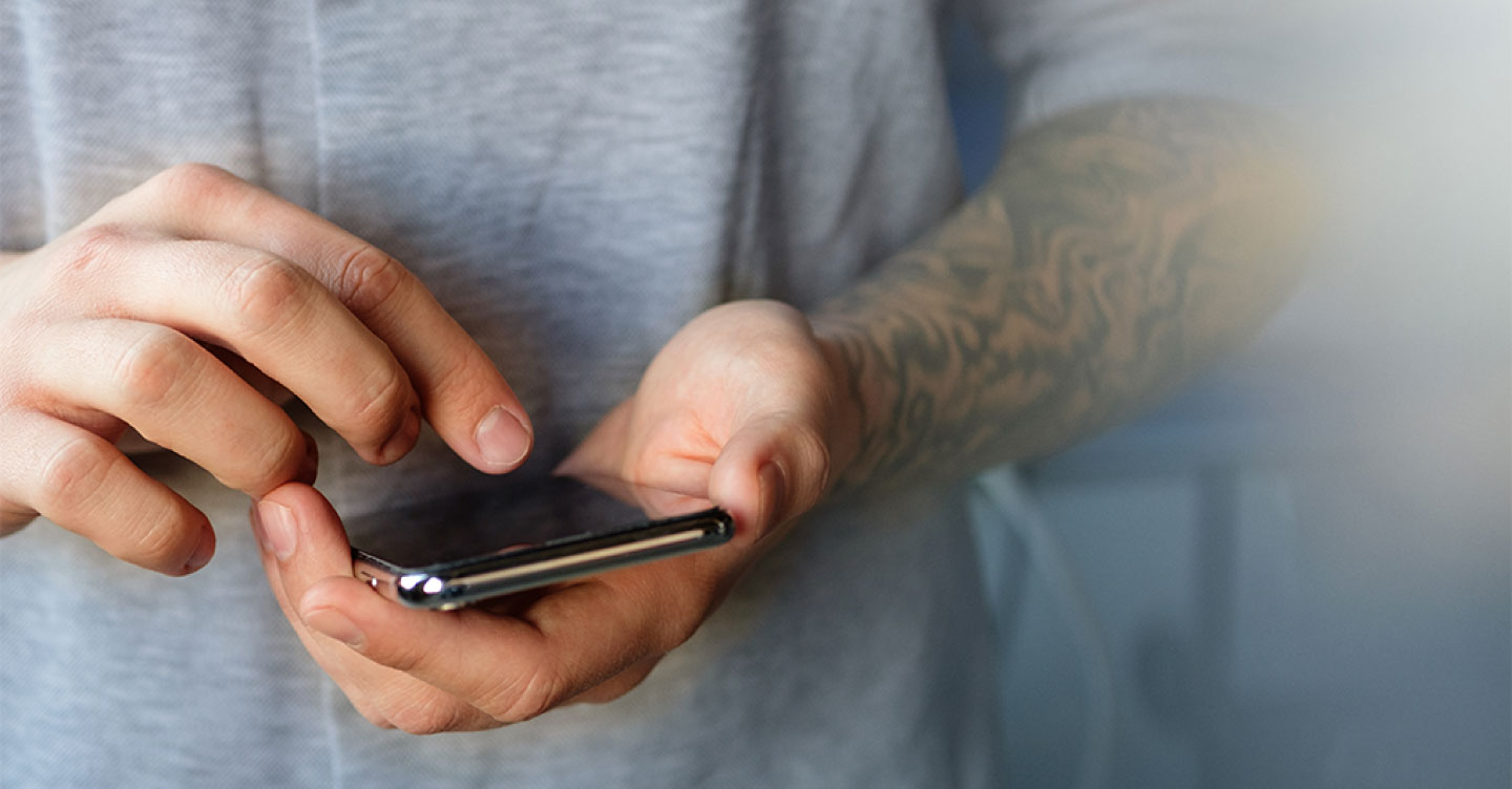 Ein Mann hält ein Smartphone in der Hand und tippt mit dem Zeigefinger darauf